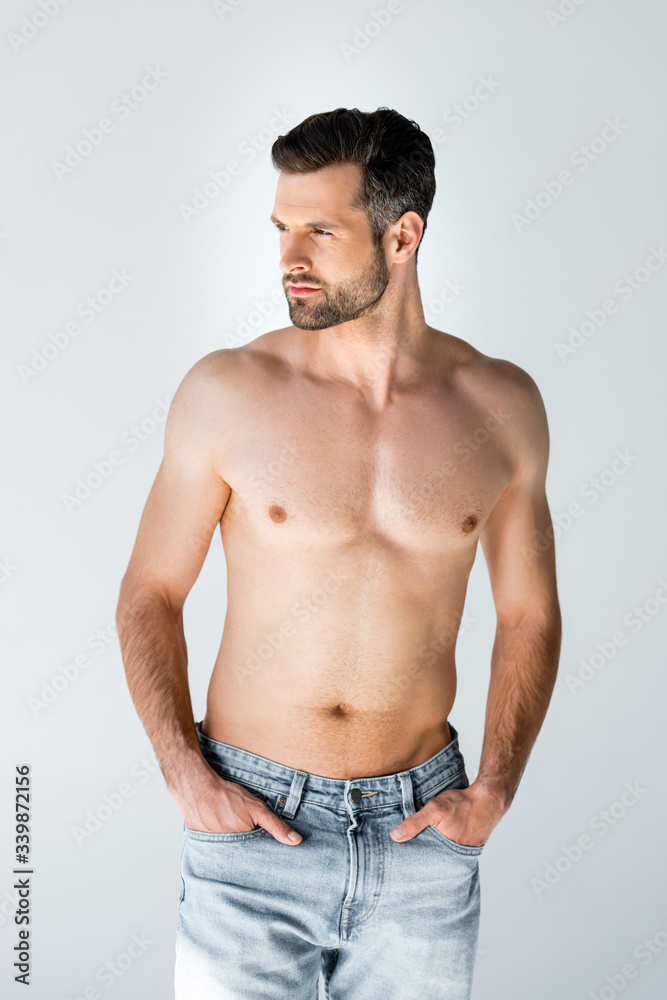 shirtless man in blue jeans standing with hands in pockets isolated on grey shirtless man in blue jeans standing with hands in pockets isolated on grey