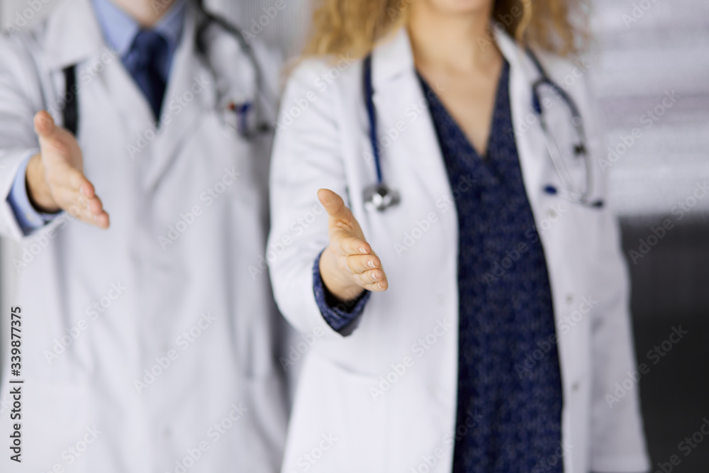 Two doctors standing and offering helping hand for shaking hand or saving life. Medical help, countering viral infection and medicine concept Two doctors standing and offering helping hand for shaking hand or saving life. Medical help, countering viral infection and medicine concept