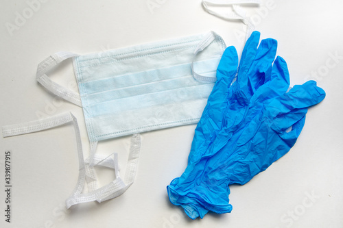Medical disposable mask and blue gloves on a white background. Personal protective equipment.