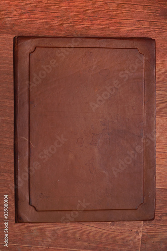 Antique brown aged leather cover with different spots on a wooden brown background