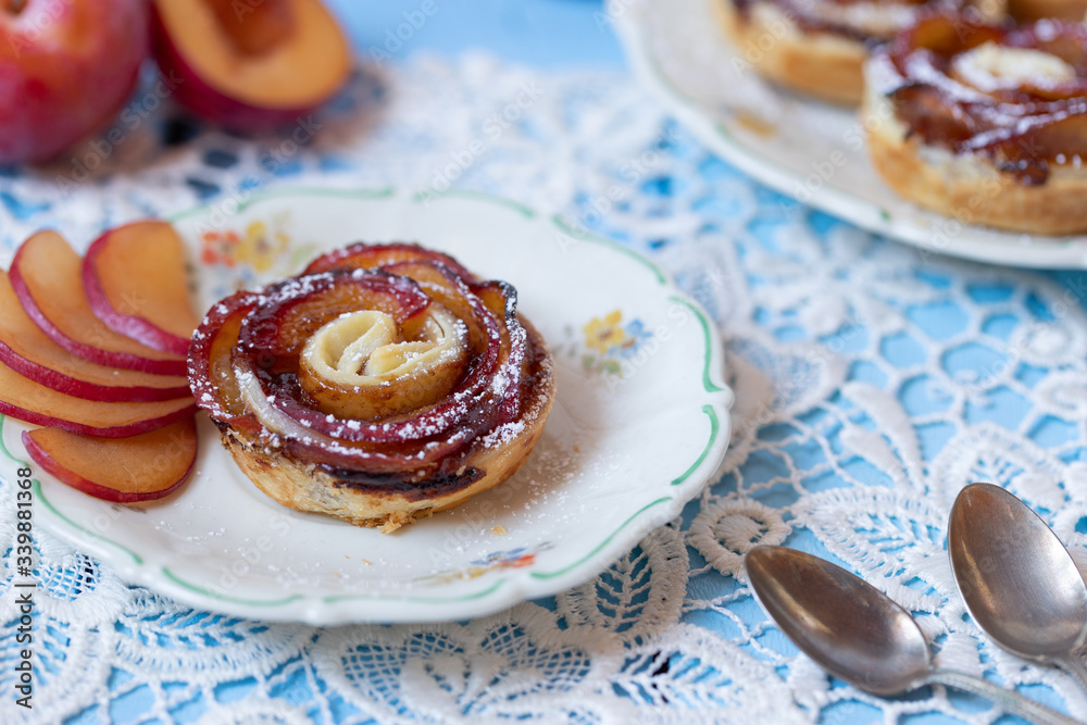 gebackene Blätterteigrosen mit Pflaumen und Puderzucker auf hellen ...
