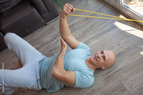 A middle-aged man plays sports at home on the floor.