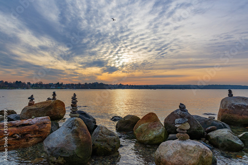 Small towers of rocks line the shore of English Bay in Vancouver Canada as the sun sets on a winter afternoon
