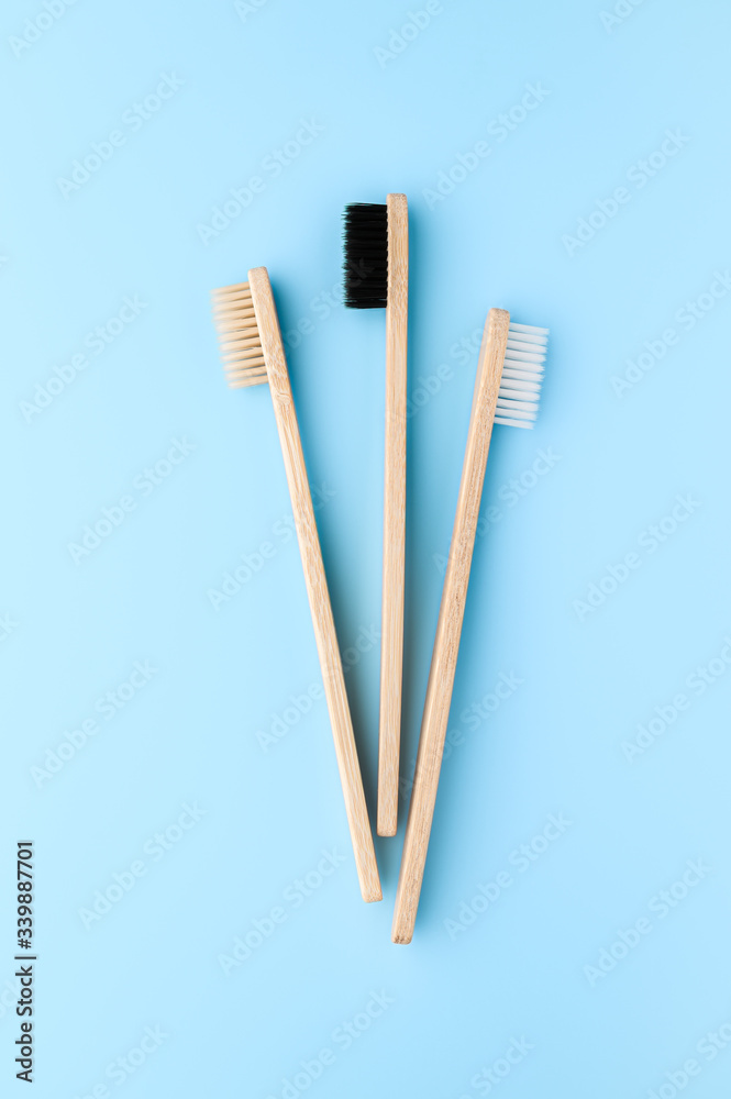Zero waste and no plastic concept. Three eco friendly bamboo toothbrushes on a light blue surface. Top view, vertical orientation. Layout natural organic hygiene products.