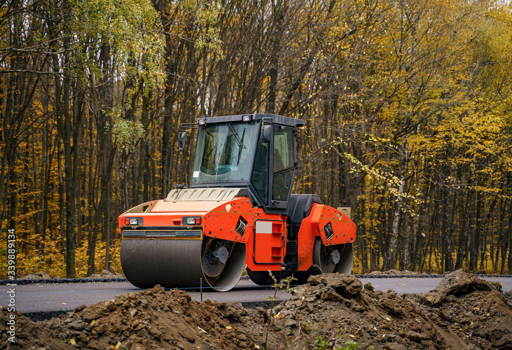 Road repair, compactor lays asphalt. Heavy special machines. Asphalt paver in operation. Side view. Closeup.