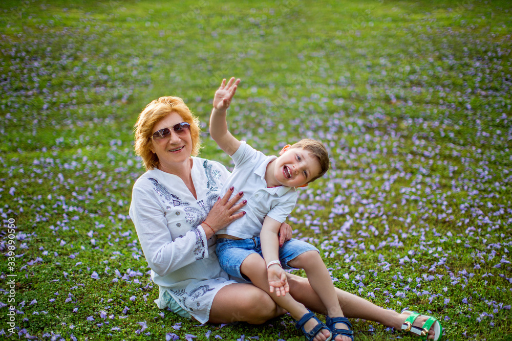 A boy and his grandmother are resting on the nature on the grass