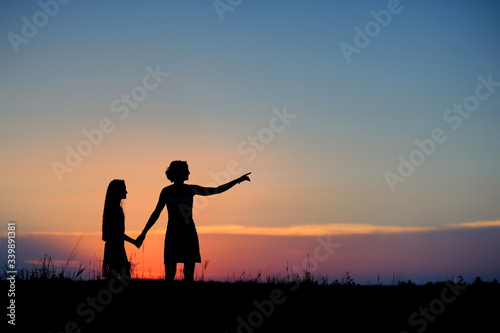 Silhouettes of mother and daughter against the sunset sky.