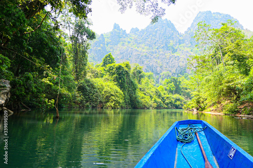 Green jungles in mountains from the wooden boat. Green forest and water reflection.