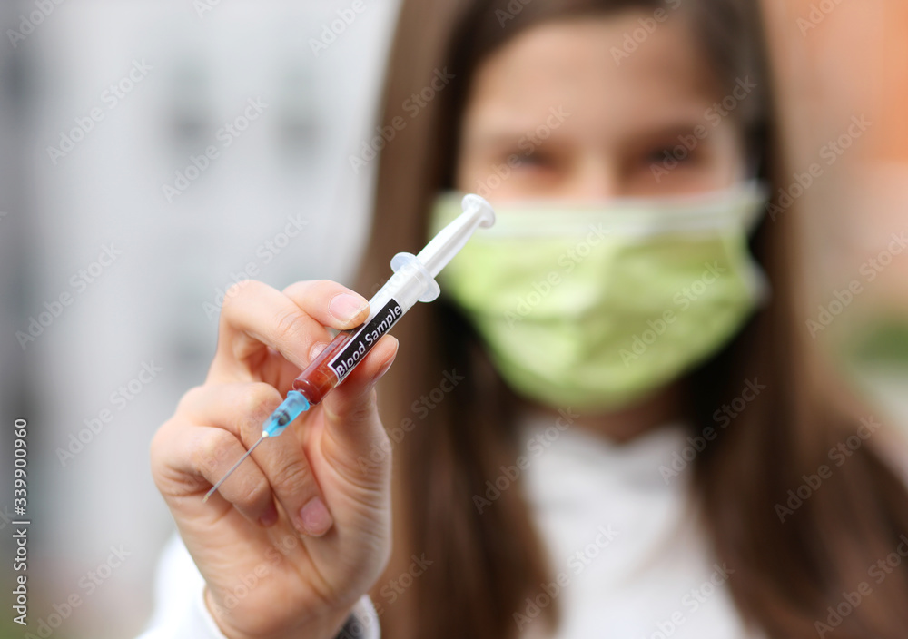 young nurse with syringe containing a blood sample for analysis young nurse with syringe containing a blood sample for analysis