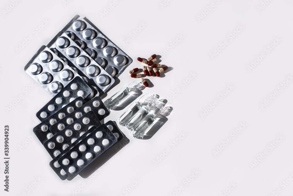 Medicines: white plain breakable tablets in transparent sticks, in metal non-trasparent sticks, overencapsulated tablets, ampuls with anti-virus vaccine on white background. Copy space. Medicines: white plain breakable tablets in transparent sticks, in metal non-trasparent sticks, overencapsulated tablets, ampuls with anti-virus vaccine on white background. Copy space.