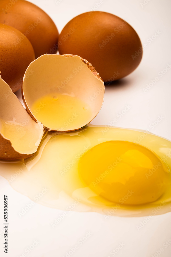 A broken chicken egg and scattered eggs on a white background. Close up. A broken chicken egg and scattered eggs on a white background. Close up.