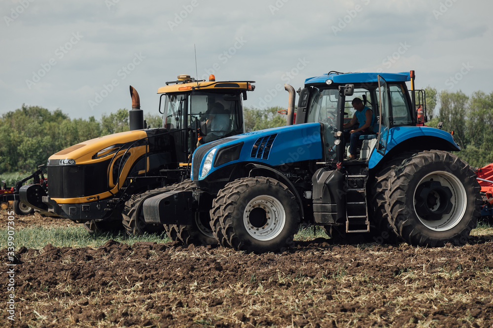 yellow and blue tractor stand in a field during a test drive demonstrating power yellow and blue tractor stand in a field during a test drive demonstrating power