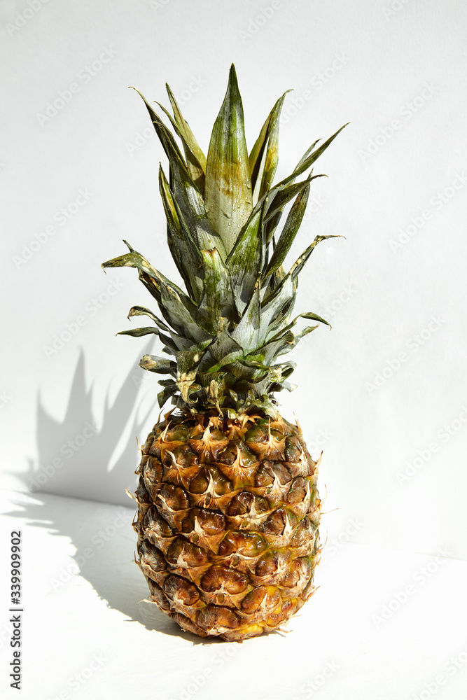 Fototapeta premium Whole ripe tropical pineapple with shadow on a white background.