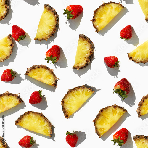 Beautiful bright pattern of ripe strawberries and pineapple slices on a white background.