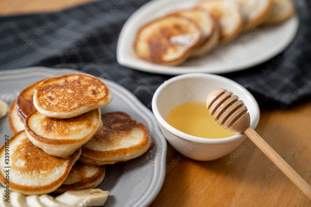 Delicious fresh pancakes with maple syrup or bee honey with a wooden stick.