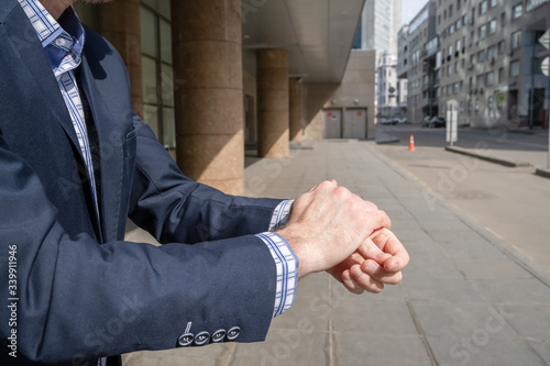 Businessman in a blue suit using small portable antibacterial sanitizer applying antiseptic for washing hand on the street. protection from bacteria and virus. hygienic gel. Coronavirus. photo