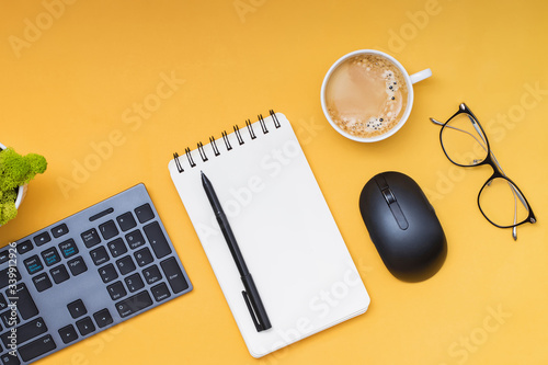 Keyboard, computer mouse and cofffe on yellow background photo