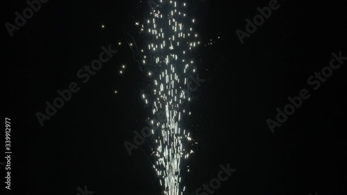 Slow motion shot of fireworks producing an upward shower of sparks against a black background. Commonly known as a gerb, this pyrotechnic is also called a sparkling fountain or waterfall.