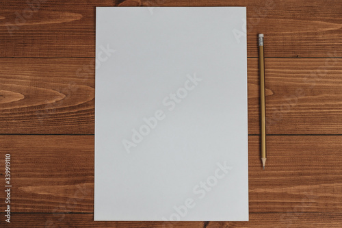 Blank paper and ordinary pencil on a wooden table. View from above
