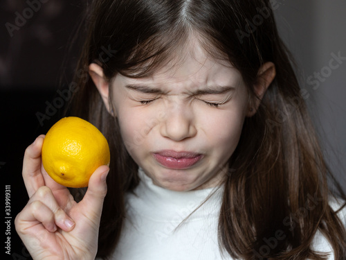 Photography Small / young girl tastes a lemon, grimace on her face