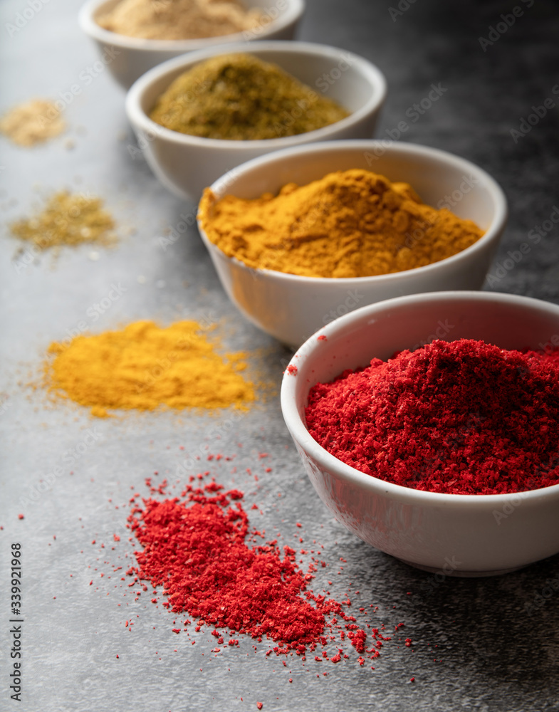 various indian spices in bowls on dark concrete background