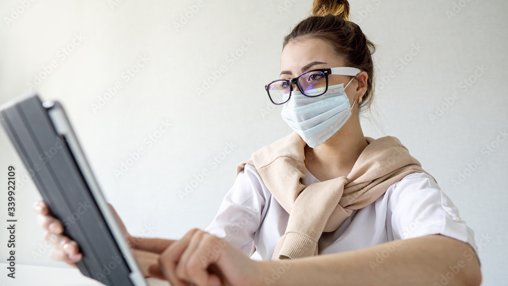 serious girl in a surgical mask works at home on a tablet. girl in hipster glasses works at home, self-isolation. Coronavirus outbreak or Covid-19, Concept of Covid-19 quarantine
serious girl in a surgical mask works at home on a tablet. girl in hipster glasses works at home, self-isolation. Coronavirus outbreak or Covid-19, Concept of Covid-19 quarantine
