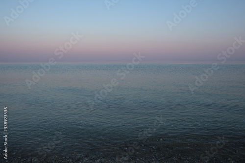 The calm surface of the sea after sunset. Delicate shades of clear sky. Halkidiki, Greece.
