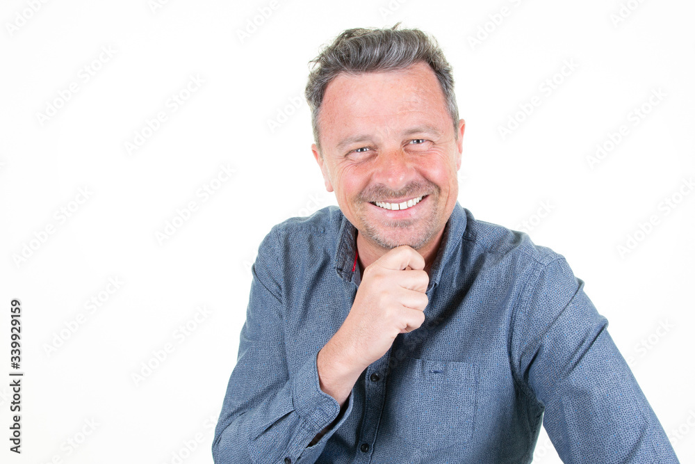 handsome business man wearing elegant blue shirt looking confident at camera smiling with hand raised on chin in white background handsome business man wearing elegant blue shirt looking confident at camera smiling with hand raised on chin in white background