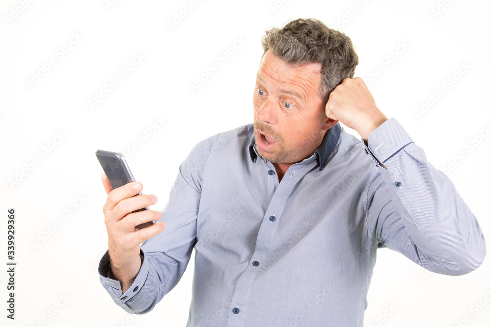 Portrait of surprise handsome man texting looking holding mobile phone in white background Portrait of surprise handsome man texting looking holding mobile phone in white background