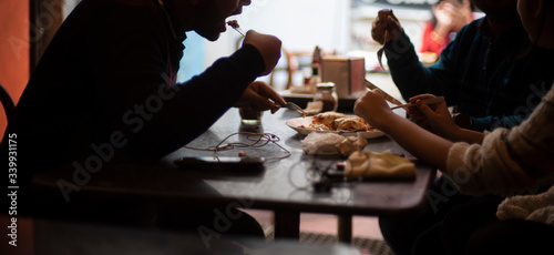 Silhouette of a group of young friends having lunch in a restaurant in a festive day. Indian lifestyle.