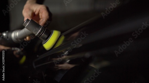 Car detailing - Hands with orbital polisher in auto repair shop. Selective focus. 
