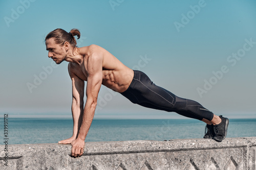 Workout Exercise. Closeup Of Topless Healthy Handsome Active Man With Fit Muscular Body Doing Push Ups outdoors. Sporty Athletic Male Exercising At Sea Shore , Training Outdoor. Sports Concept