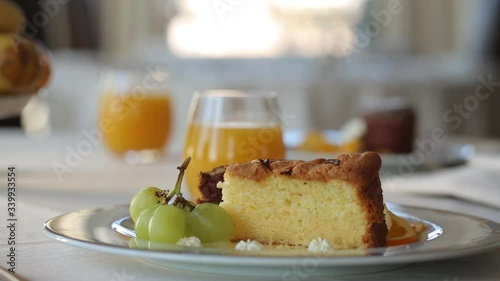 Camera slowly moves over the breakfast table, at the end it focuses on the cupcakes on plates and orange juice. 
