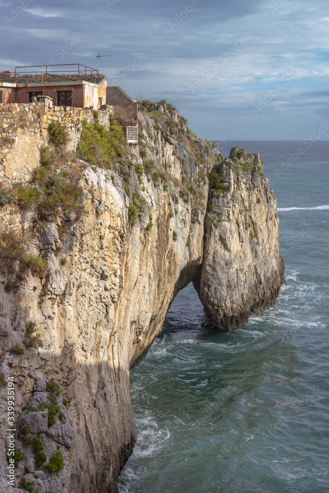 House of the writer. Secluded place. House on the edge of the earth. High cliff. Rock by the sea. Waves in the grotto. Spanish coast. Unity with nature. Rocky coast. Surroundings of Castro Urdiales.