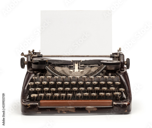 Old vintage typewriter and a blank sheet of paper inserted. Isolated on white background. photo