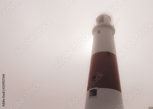 Obraz na płótnie Portland Bill lighthouse on a foggy summer morning as the sun tries to break through behind, Portland, Dorset, UK w salonie