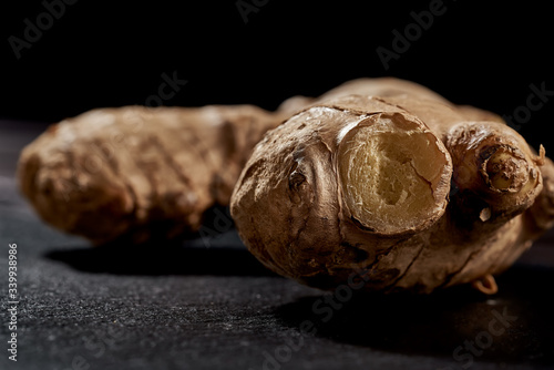 Ginger root in macro photo on black background. side view. volume mature product. Against viruses and diseases