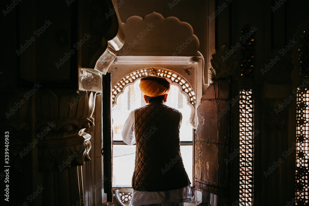 Man waring turban looking out the window at Jodhpur fort