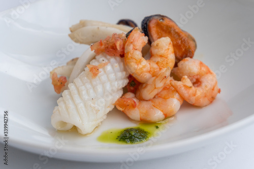 Fancy FISH AND SEAFOOD with soup on a white plate with a white background