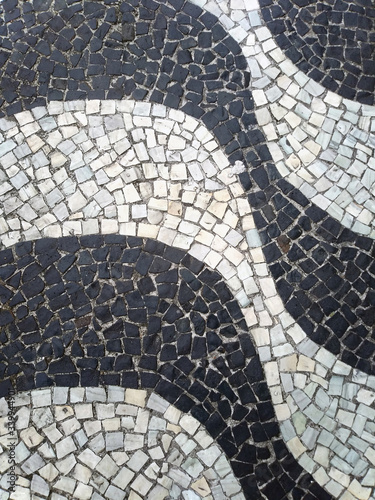 Sidewalk of Copacabana Beach, Brazil. Promenade of Rio de Janeiro. Background, urban texture. Real pattern made with small black and white stones. Top flat view.