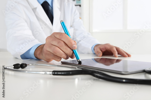doctor hand touch screen of digital tablet writing prescription at desk in medical office close up
