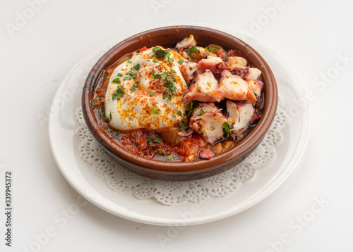 Octopus ratatouille with an egg in a clay pot dish with a white background