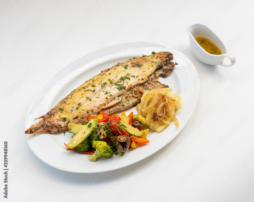 Sole meunière fish with grilled vegetables and caramelized onions on a white plate with white background. LENGUADO MENIER Sole meunière fish with grilled vegetables and caramelized onions on a white plate with white background. LENGUADO MENIER