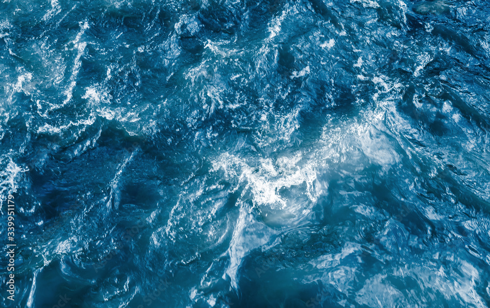 Deep blue stormy ocean water with splashes and foam