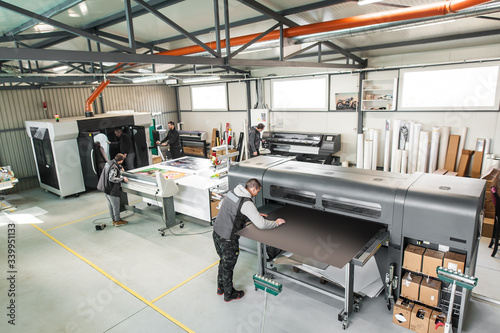 Foto Large group of technicians works in printing printshop press hall