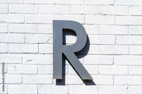 The letter R in steel on a brick wall 