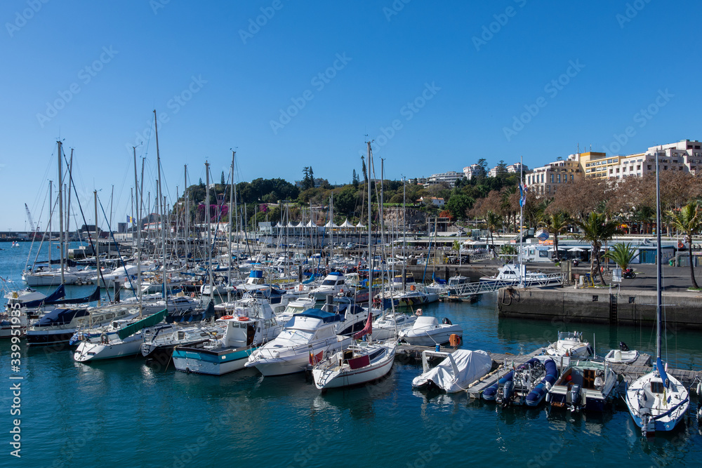 View over Funchal harbour with a lot of sailboats and and a blue sky in background
