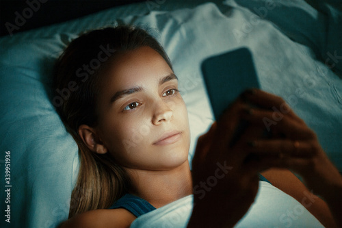 Young beautiful womanl in bed using mobile phone late at night at dark bedroom, internet addiction concept