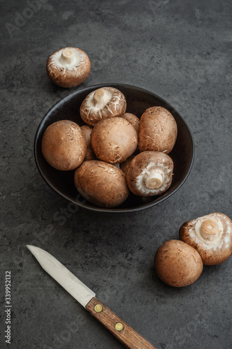 Obraz na płótnie Braune Champignons in einer Schüssel zusammen mit einem Messer auf einem dunklen Hintergrund w salonie