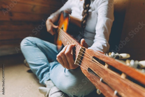 Stay Home Stay Safe. Young woman sitting at home and playing guitar, hands close up. Teen girl learning to play song and writing music. Hobby lifestyle relax Instrument leisure education concept.